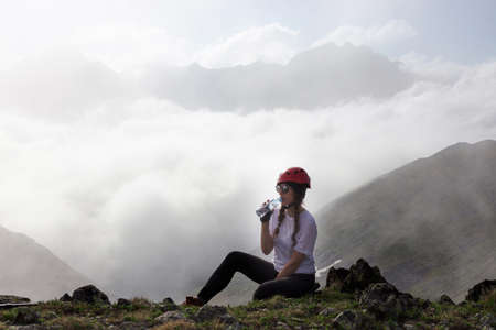 Woman tourist drinks water at the top of a mountain. Travel lifestyle adventure concept active outdoor recreation hiking.の写真素材