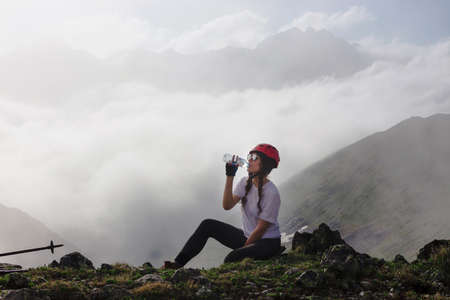 Woman tourist drinks water at the top of a mountain. Travel lifestyle adventure concept active outdoor recreation hiking.の写真素材