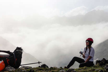 Woman tourist drinks water at the top of a mountain. Travel lifestyle adventure concept active outdoor recreation hiking.の写真素材