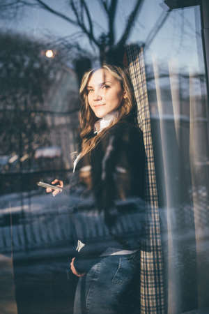 The woman looked out the window of the cafe. A young girl looks through a meeting through the window.の写真素材