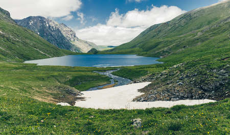 Lake and Mountains spring landscape, an epic alpine view, blue water and green meadows. Traveling in the wild.の写真素材
