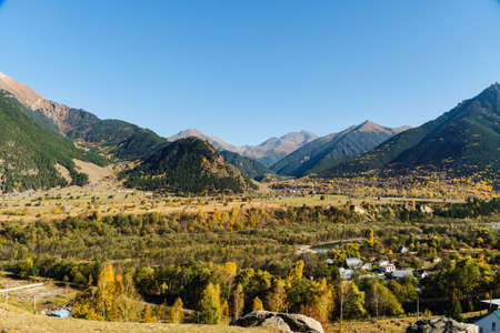 Colorful scene of mountains on a sunny day. Autumn landscape view of the valley with colorful trees and high peaks.の写真素材