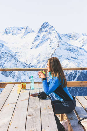 Woman traveler holding a cup of tea, enjoying hot drink in cafe at ski resort. Sunbathing in snow the top of the mountain.  Adventure, wanderlust, Travel active lifestyle concept. outdoor recreation.の写真素材