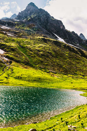 Stunning view of a green mountain hill located near a clean lake on a sunny spring day. The concept of rest away from civilization.の写真素材