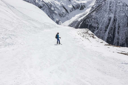 Woman snowboarder on a slope winter on a background of high mountains. Travel Lifestyle recreation and extreme concept, activities sport outdoors, adventure vacations. View landscape ski resort.の写真素材