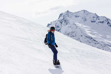 Sports background young woman snowboarder on a slope winter. Travel Lifestyle recreation and extreme adventure concept, activities vacations outdoor in holidays. Ski resort in the mountains view.の写真素材