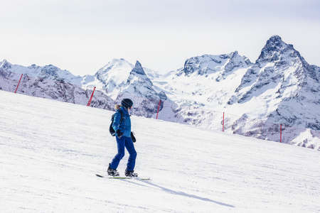 Young woman snowboarder on a slope winter. Travel Lifestyle recreation and extreme concept, activities adventure  vacations outdoor in holidays. Ski resort in the mountains view. Sports background.の写真素材