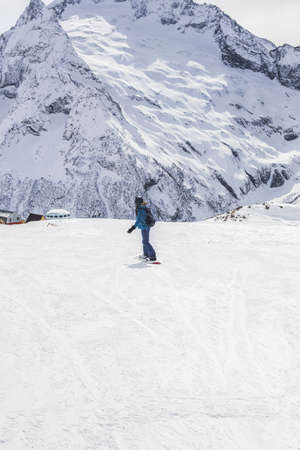 Young woman snowboarder on a slope winter on a background of mountains. Travel Lifestyle recreation and extreme concept, activities adventure vacations. Ski resort in the mountains view. Winter sport.の写真素材