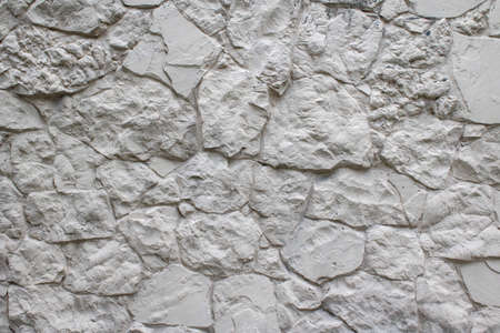 Wall natural facade stone decoration background texture painted white. Masonry as a cladding of...