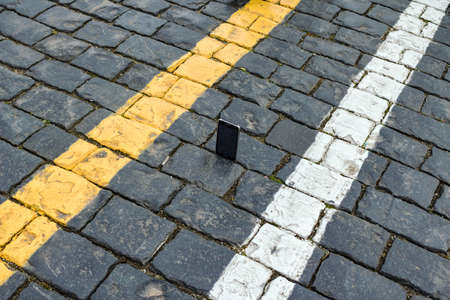 Abstract picture, smartphone on the stones paving the streets with road markings with a pedestrian...