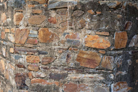 Wall texture background stone. Grunge facing coarse, rough stone or rock texture of mountains. Aged grungy stonework city. Damage front decor house.の写真素材