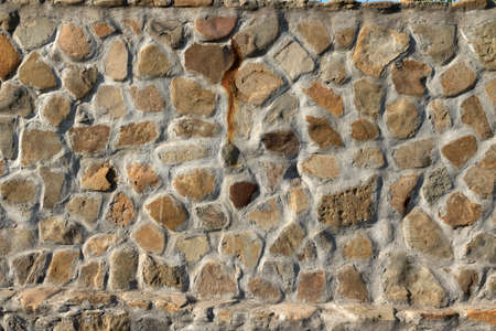 Wall texture background stone. Grunge facing coarse, rough stone or rock texture of mountains. Grungy aged stonework city. Damage front decor house.の写真素材