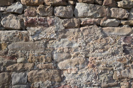 Stone wall grunge texture background. Rough old stone or rock of mountains. Grungy vintage fortress granite and sandstone. Front antique decor house. General layout of stone masonry.の写真素材