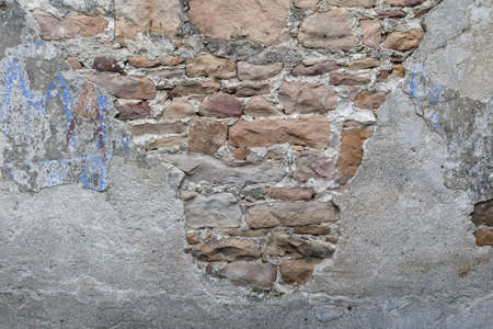 Grunge background stone wall textured. Rough old stone or rock texture of mountains. Coarse facing, grungy vintage fortress granite and sandstone. Front antique decor house. General layout of stone masonry.の写真素材