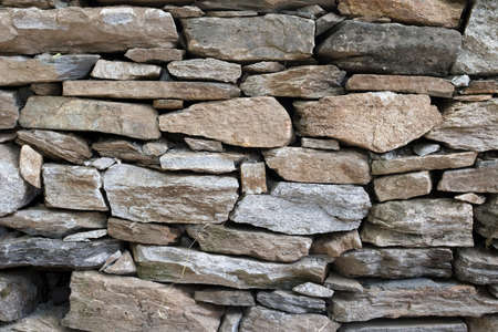 Stone rock texture background. Natural stone masonry without mortar and cement, an old fortress building. Castle wall made granite of blocks. Wall rough old piece rock of mountains.の写真素材