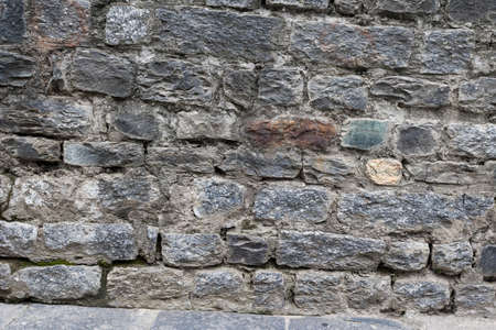 Grunge texture stone wall background. Coarse facing, rough old stone or rock texture of mountains. Grungy aged stonework city. Front antique decor house. General layout of stone masonry.の写真素材