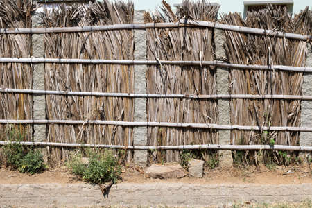 Exotic tropical village, simple buildings with stone pillars, walls made of reed, palm leaves, bamboo. Natural materials for simple home in the tropics, India. Environmental conditions in the village.の写真素材