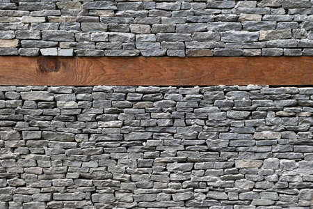 Wooden bands and dry-stacked rubble stone masonry. Abstract background texture mixed for earthquake resistance old stone walls. Traditional buildings of the Himalayas, Nepal.の写真素材
