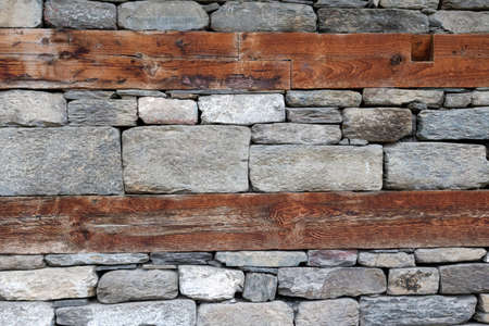 Wooden bands and dry-stacked rubble stone masonry. Abstract background texture mixed for old stone walls. Tibetan village house. Traditional building technology Himalaya, Nepal.の写真素材