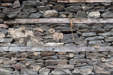 Wooden bands and dry-stacked rubble stone masonry. Abstract background texture mixed for old stone walls. Tibetan village house. Traditional building technology Himalaya, Nepal.の写真素材
