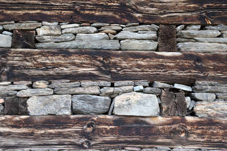 Wooden bands and dry-stacked rubble stone masonry. Abstract background texture mixed for old stone walls. Traditional building technology Himalaya, Nepal.の写真素材
