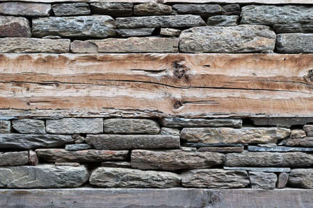 Wooden bands and dry-stacked rubble stone masonry. Abstract background texture mixed for old stone walls. Tibetan village house. Traditional building technology Himalaya, Nepal.の写真素材