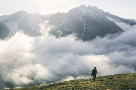 Woman hiking at sunset mountains with heavy backpack Travel Lifestyle wanderlust adventure concept summer vacations outdoor alone into the wildの写真素材