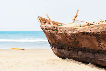 Vintage handmade fisherman boat with fishing nets on the beach near the ocean in Arambol, Goa,...
