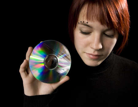 Redhead girl holding a compact disc. Lit with studio lighting, hair light and two umbrelled strobes.の写真素材