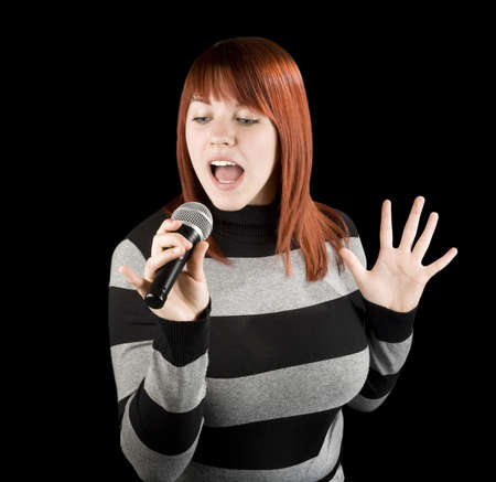 Happy beautiful redhead girl singing on a microphone, karaoke.Studio shot.