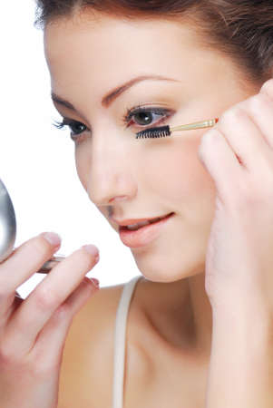 Cute young adult woman  applying maskara - beauty concept