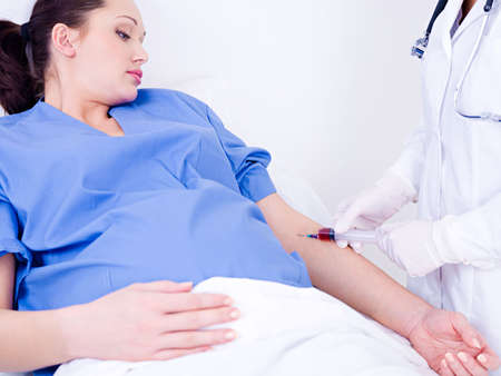 Doctor takes blood on the analysis from a vein from the pregnant womanの写真素材