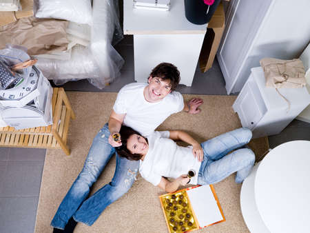 Smiling happy young couple lying on the floor and celebrating new home - high angleの写真素材