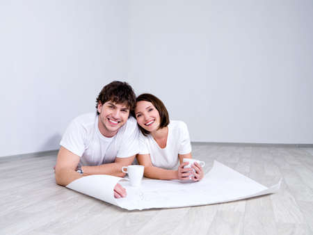 Young couple lying on the floor with plan of new roomの写真素材