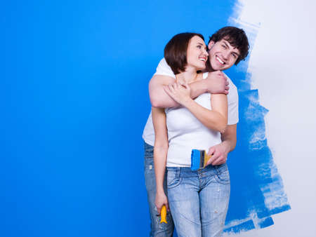 Joyful happy embracing loving couple standing near the painted wallの写真素材