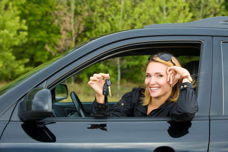 Beautiful young happy woman in the new car with keys - outdoorsの写真素材