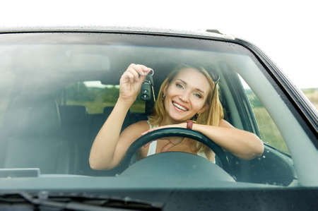 Beautiful young happy woman in the new car with keys - outdoors