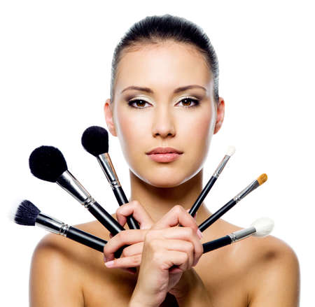 Beautiful woman with makeup brushes near her face - isolated on white Beautiful woman with makeup brushes near her face - isolated on white