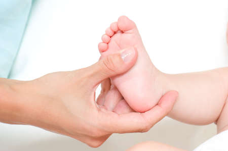 Mother making massage of child's foot isolated on white の写真素材