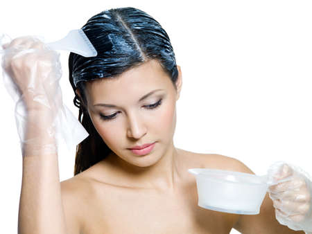 Beautiful  woman dyeing brown hairs - isolated on whiteの写真素材