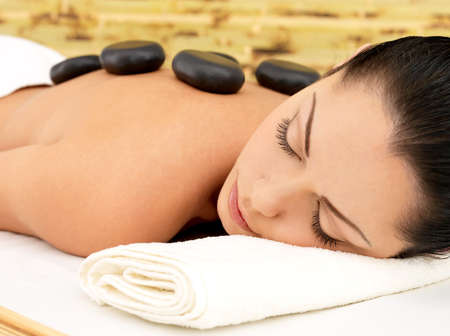 Stone massage for young woman at beauty spa salon. Recreation therapy. の写真素材