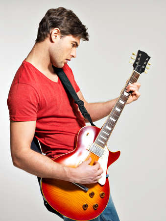 Guitarist plays on the electric guitar with bright emotions on grey  backgroundの写真素材