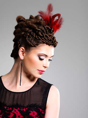 Beautiful adult woman with fashion hairstyle with red feather in hairsの写真素材
