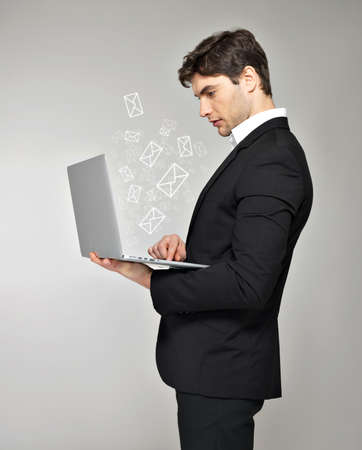 Business man with laptop in hand and mail icon over grey backgroundの写真素材