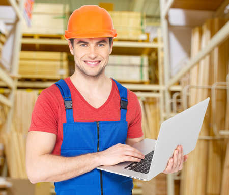 Portrait of smiling handyman with laptop working warehouse
