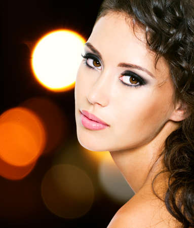 Portrait of a beautiful young woman with fashion makeup over bright night lightsの写真素材