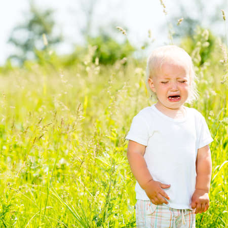 Child crying is on the nature - Toddler screaming stands ar green fieldの写真素材