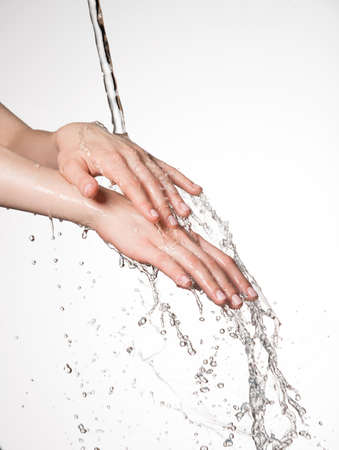 Closeup female hands under the stream of splashing water - skin care conceptの写真素材