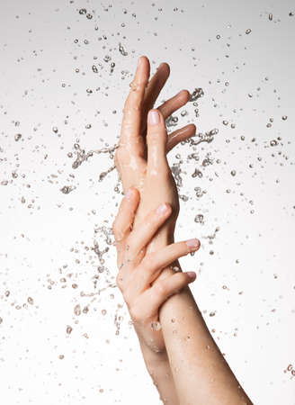 Closeup female hands under the stream of splashing water - skin care conceptの写真素材