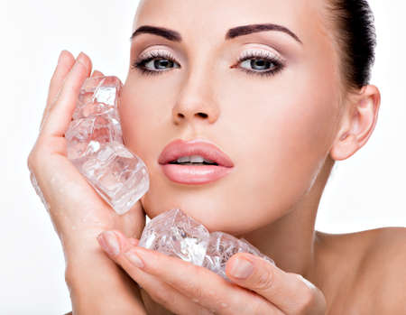Beautiful young woman applies the ice to face. Skin care concept. の写真素材